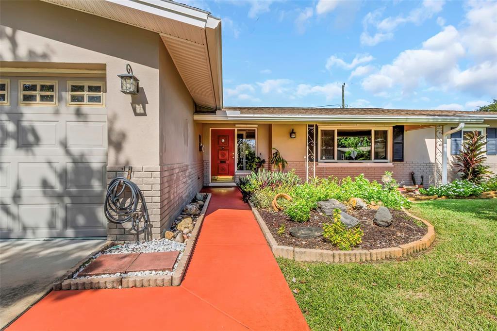 A single-story house exterior with a red walkway, a red front door, and a garage — 1773 63RD AVENUE S, ST PETERSBURG, FL