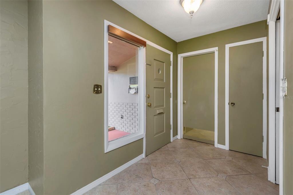 An entryway features olive green walls, tile flooring, a front door, and two interior doors — 1773 63RD AVENUE S, ST PETERSBURG, FL