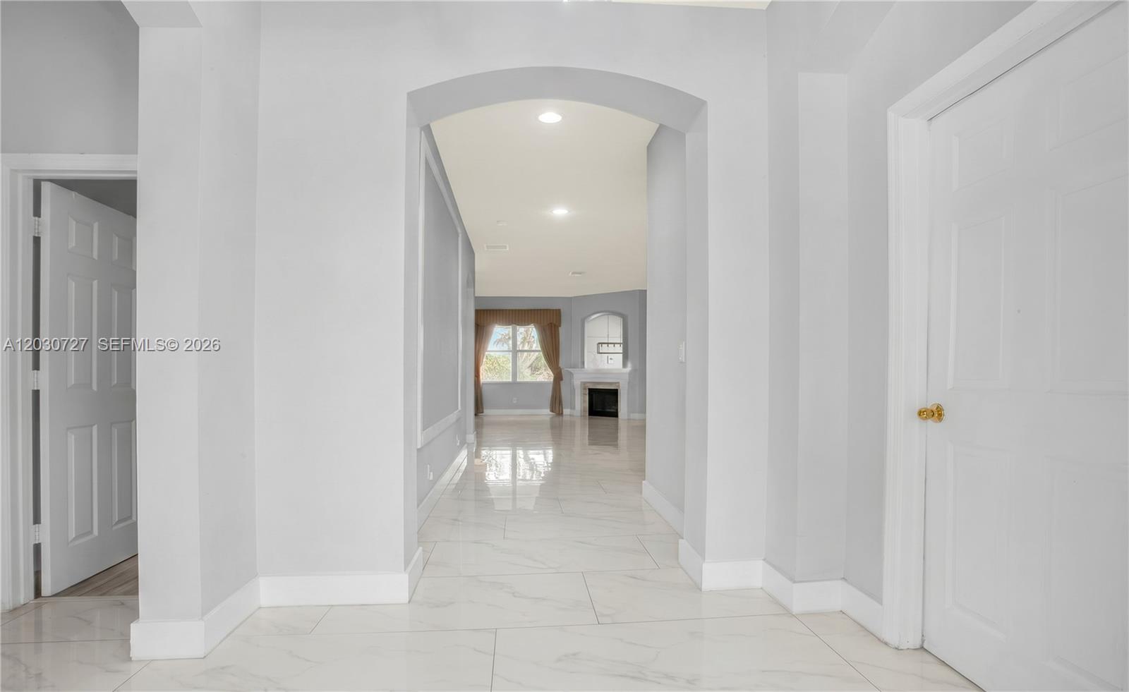 A white-tiled hallway leads through an arched opening toward a living room with a fireplace — 19548 S Whitewater Ave, Weston FL 33332, WESTON, FL