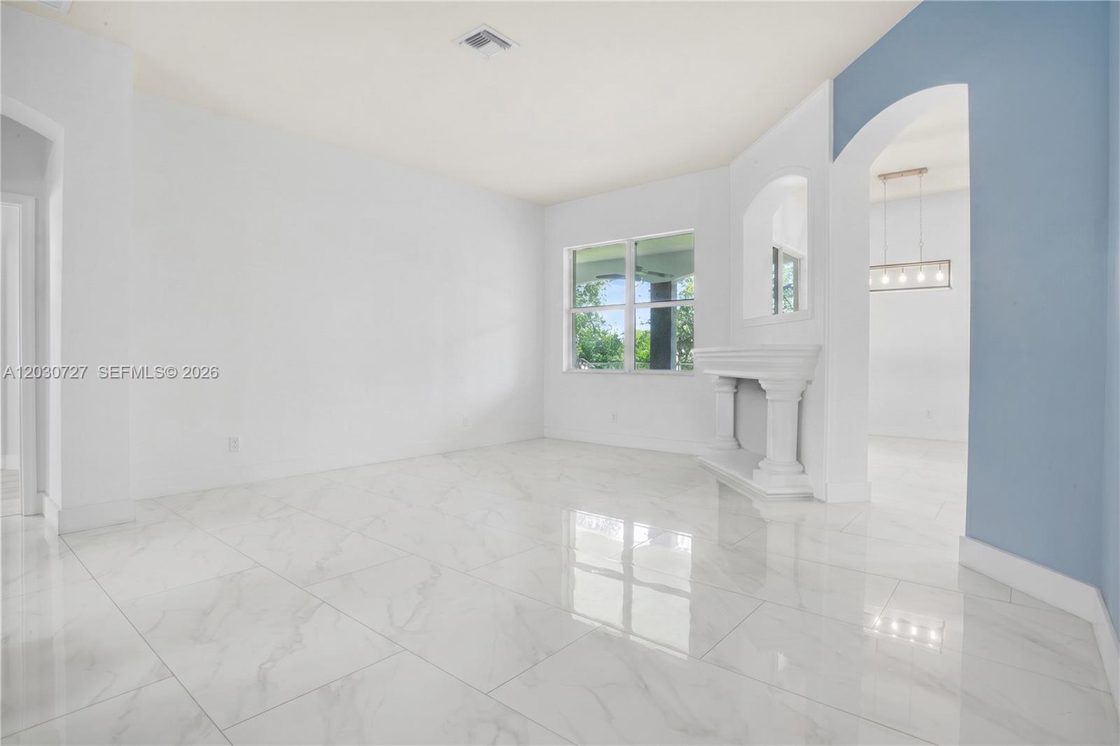 A bright room features white marble-look tile flooring, a fireplace, and an arched entryway — 19548 S Whitewater Ave, Weston FL 33332, WESTON, FL