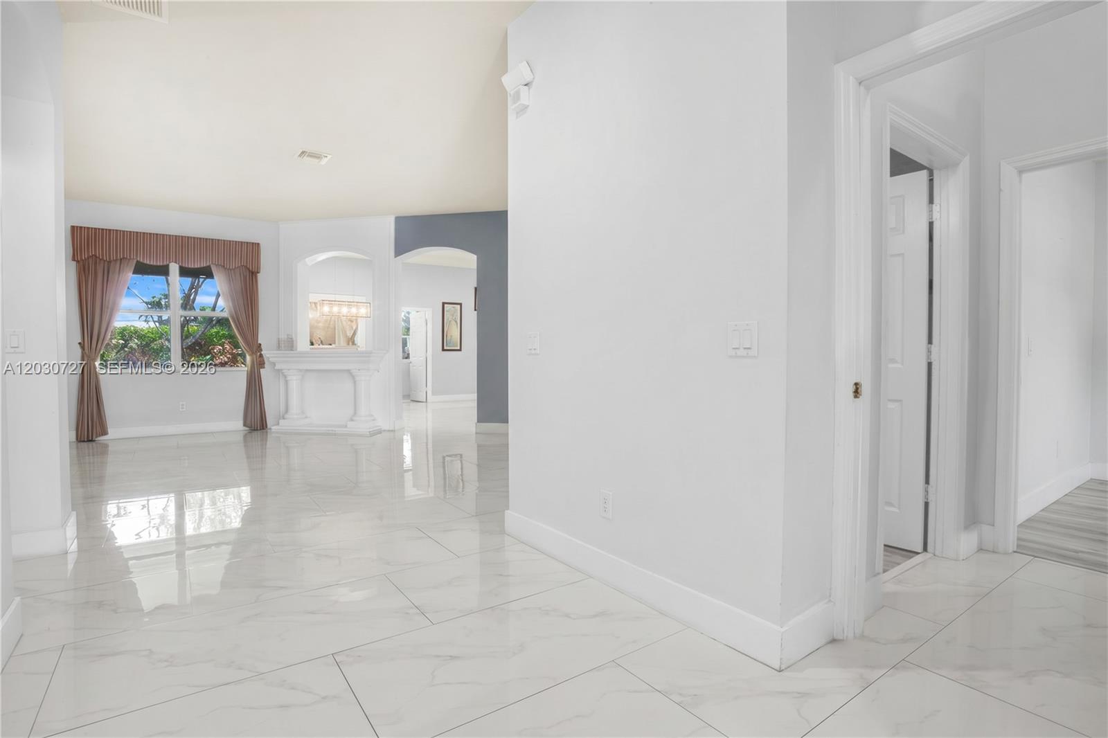 A bright, open-concept living area features white marble-look tile flooring and a decorative fireplace niche — 19548 S Whitewater Ave, Weston FL 33332, WESTON, FL