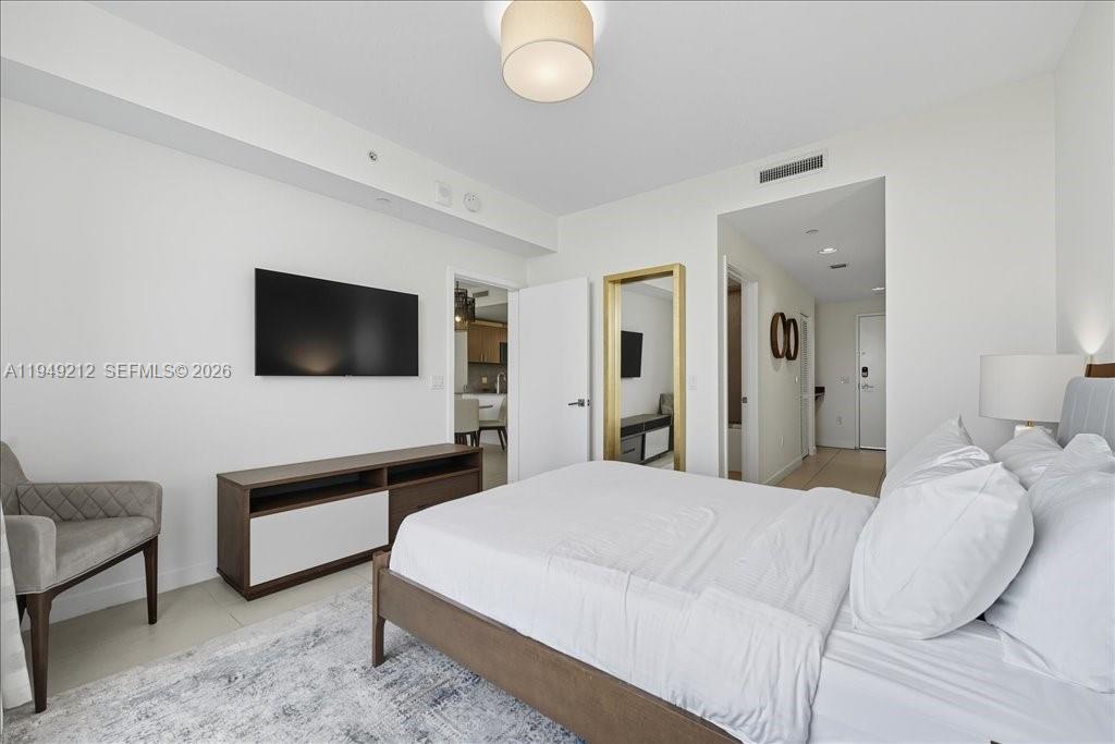 A modern bedroom features a white bed, a wall-mounted television, and a wooden media console — 5350 NW 84th Ave # 505, Doral FL 33166, DORAL, FL