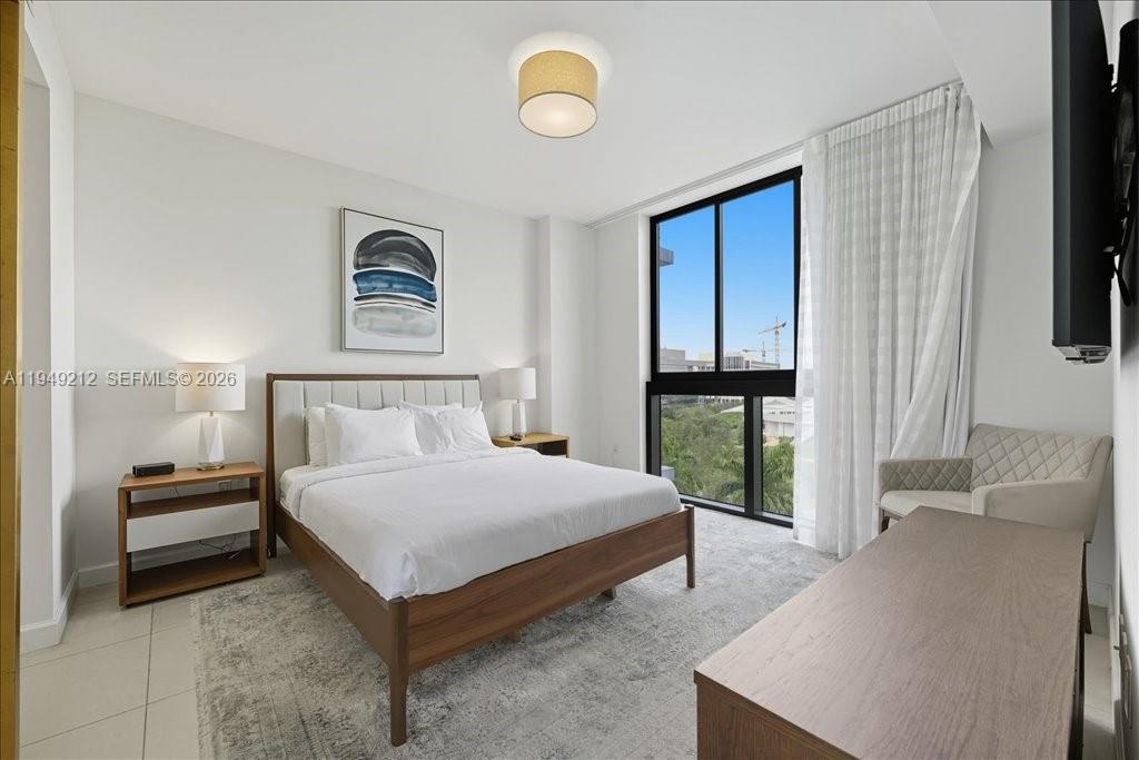 A modern bedroom features a wooden bed frame, large windows, and a neutral color palette — 5350 NW 84th Ave # 505, Doral FL 33166, DORAL, FL