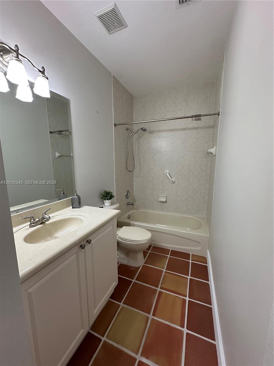 A bathroom features a vanity, a toilet, and a shower-tub combination with tiled walls — MIAMI, FL