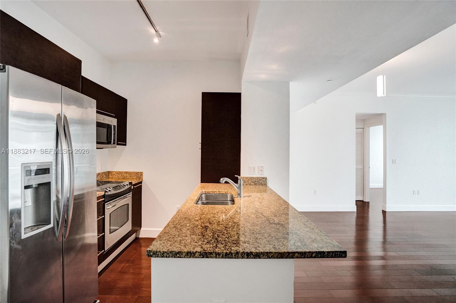 A kitchen features dark wood cabinets, granite countertops, stainless steel appliances, and hardwood floors — 950 Brickell Bay Dr # 1704, Miami FL 33131, MIAMI, FL