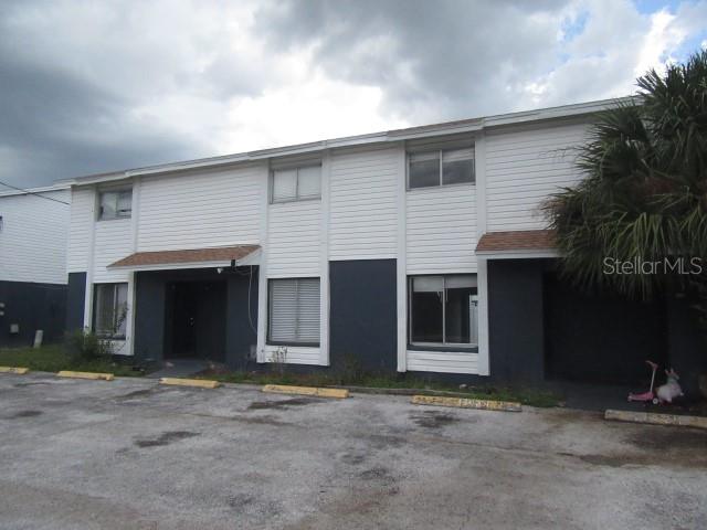 A two-story apartment building with white siding, dark gray lower walls, and a paved parking lot — 13054 N 20TH STREET, TAMPA, FL