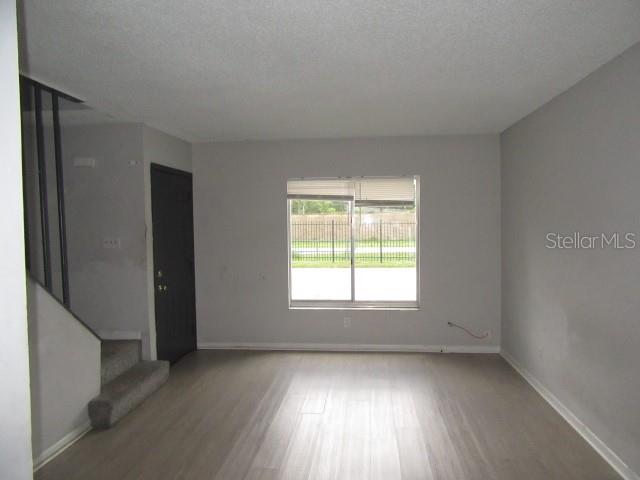 An empty living room features light wood-look flooring, gray walls, and a staircase — 13054 N 20TH STREET, TAMPA, FL