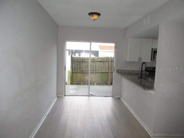 A dining area with light wood-look flooring leads to a sliding glass door and kitchen — 13054 N 20TH STREET, TAMPA, FL
