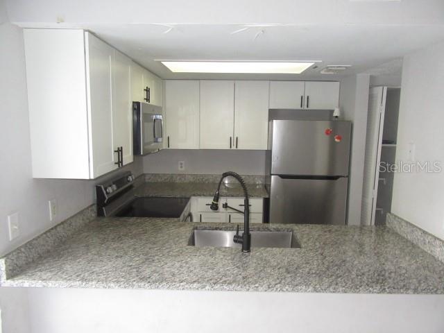 A kitchen features white cabinets, granite countertops, a stainless steel refrigerator, and a sink — 13054 N 20TH STREET, TAMPA, FL