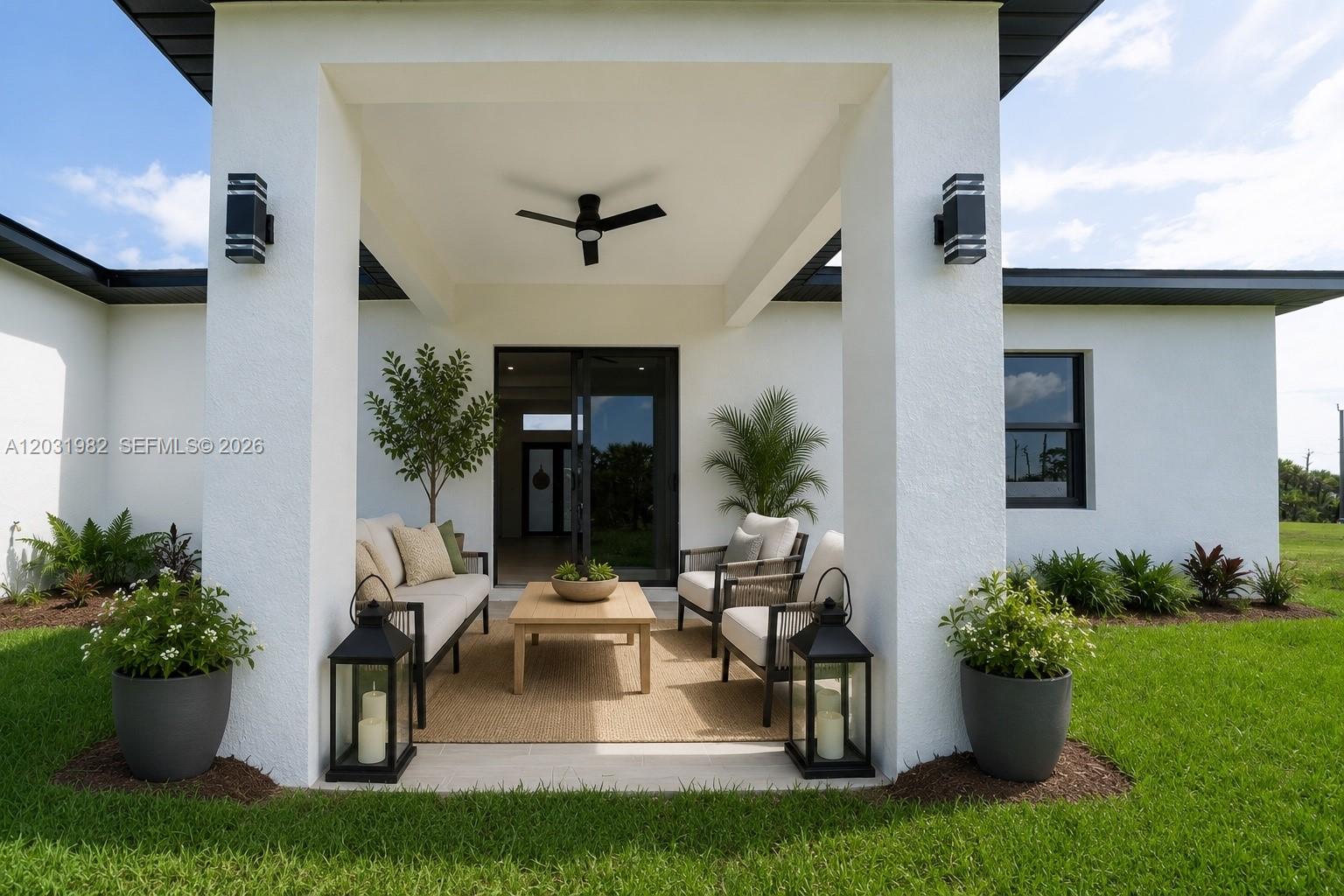 A covered patio features white columns, outdoor seating, a ceiling fan, and potted plants — 2622 22 Avenue SE, Naples FL 34117, NAPLES, FL