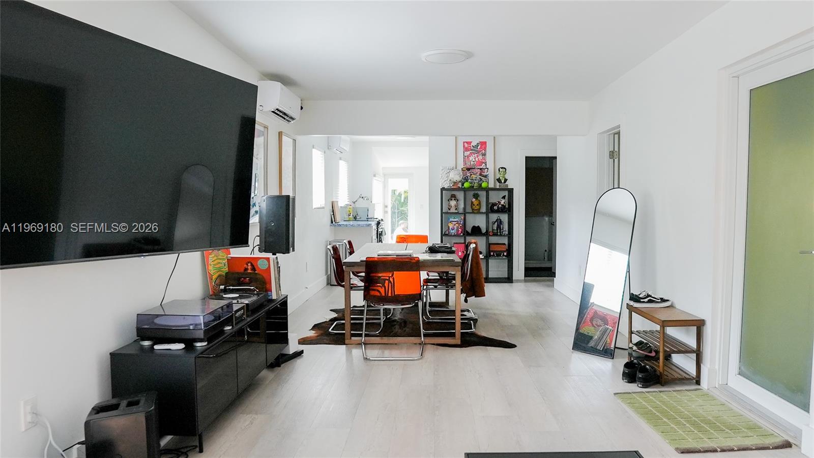 A bright living and dining area features white flooring, a large television, and modern furniture — 3010 NW 1st Ave # 0, Miami FL 33127, MIAMI, FL
