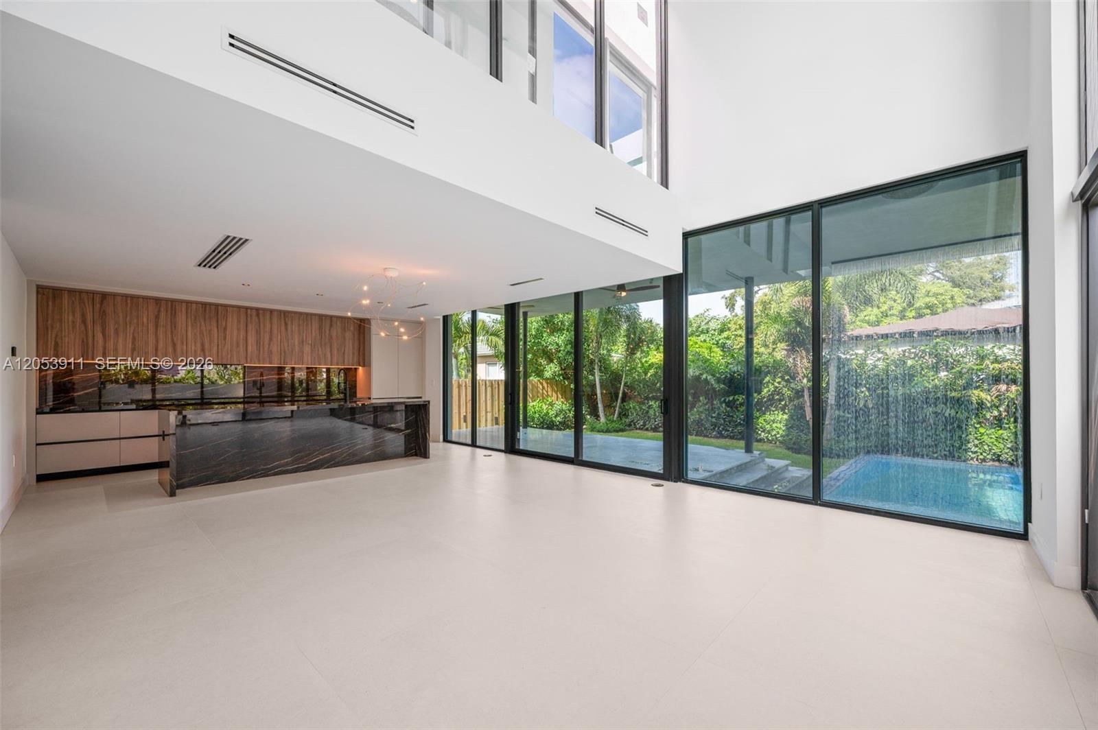 A modern kitchen with dark stone counters overlooks a backyard pool through floor-to-ceiling windows — 3310 Elizabeth St, Miami FL 33133, MIAMI, FL