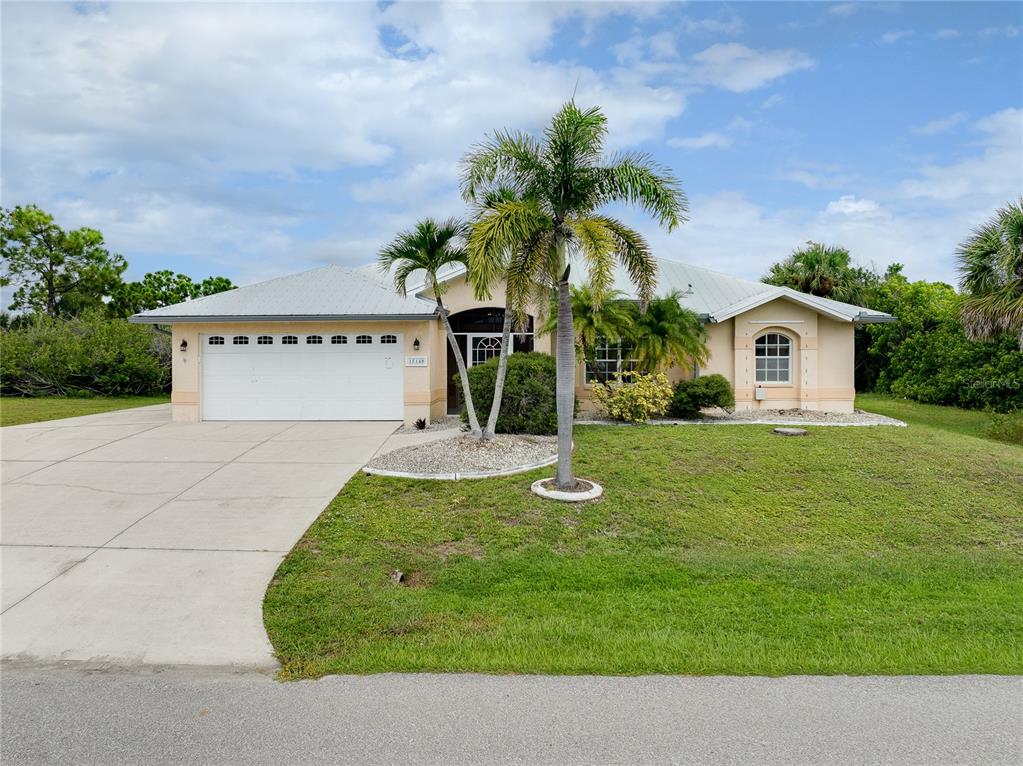 A single-story house with a white garage, metal roof, and palm trees in the front yard — 15140 LYNEBURG AVENUE, PORT CHARLOTTE, FL