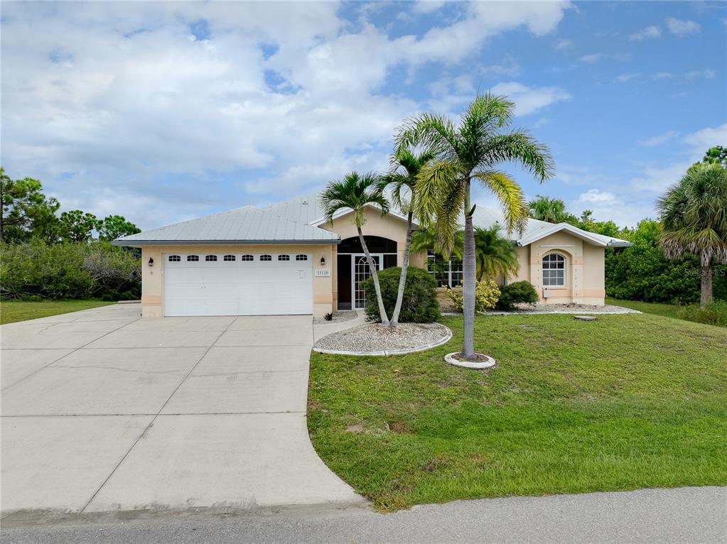 A single-story house with a white garage, metal roof, and palm trees in the front yard — 15140 LYNEBURG AVENUE, PORT CHARLOTTE, FL