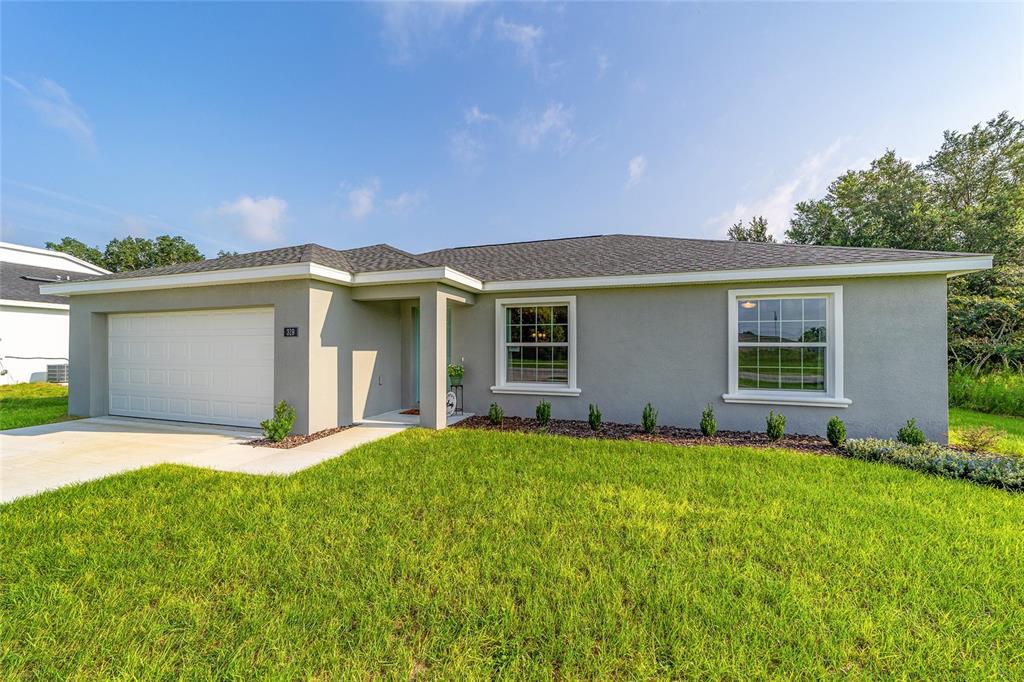 A single-story house with a gray stucco exterior, a two-car garage, and a front lawn — 66 PECAN RUN, OCALA, FL