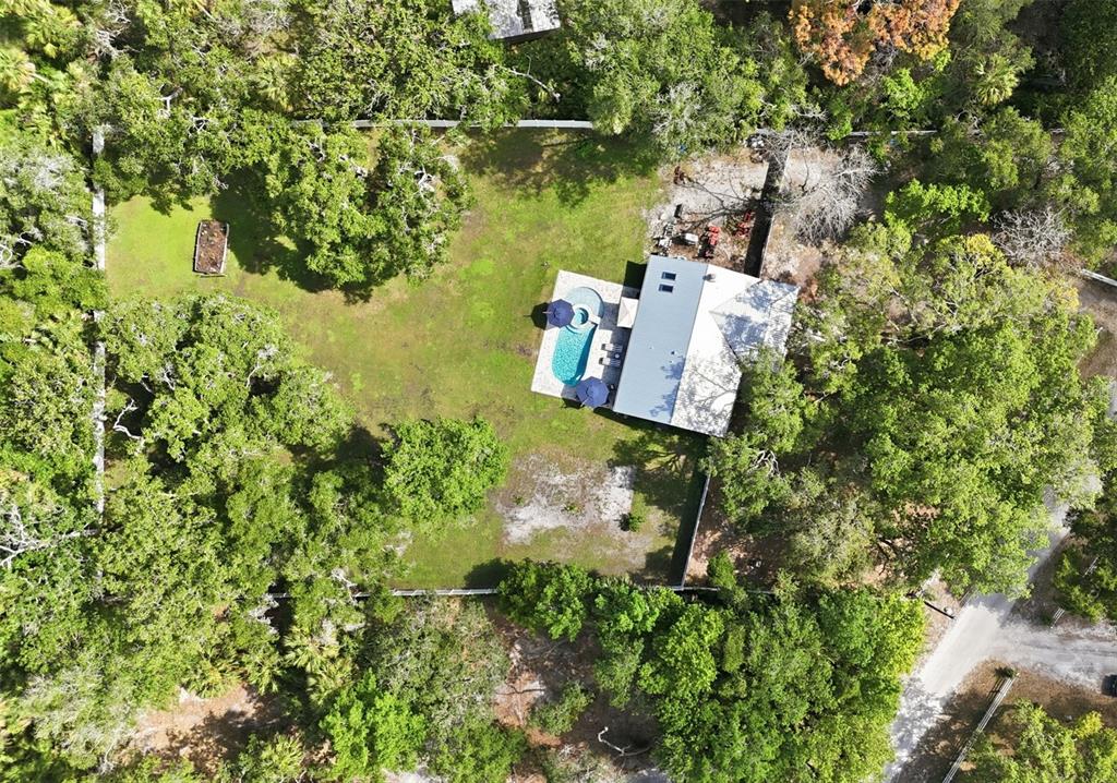 An aerial view of a house with a pool and patio in a wooded lot — 18909 JEBERT DRIVE, ARIPEKA, FL