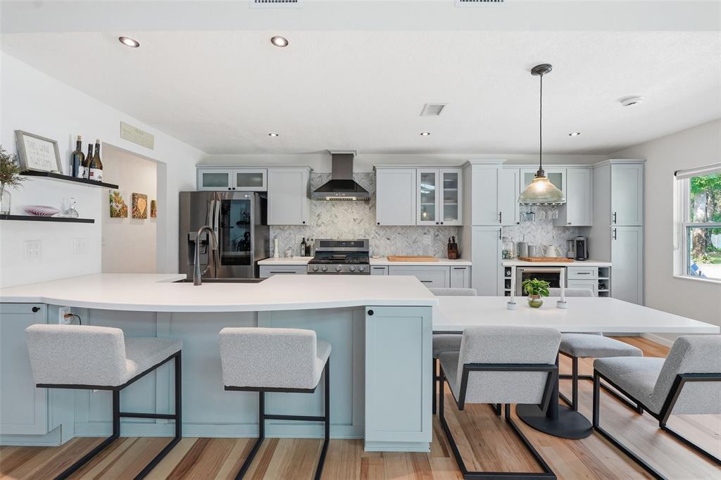 A kitchen features light blue cabinets, white countertops, a breakfast bar, and a dining area — 18909 JEBERT DRIVE, ARIPEKA, FL