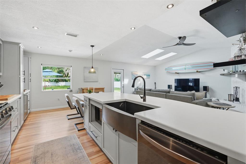 A modern kitchen features a large farmhouse sink, white countertops, and light wood flooring — 18909 JEBERT DRIVE, ARIPEKA, FL