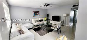 A living room features a white sofa, a coffee table, and a television on a stand — TAMARAC, FL
