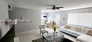 A living room with light tile floors, a white sofa, and a glass coffee table — TAMARAC, FL