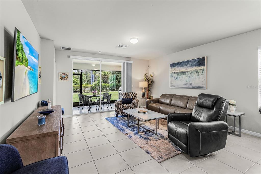 A living room features tile flooring, a leather sofa, a recliner, and a sliding glass door — 25008 E LENOX CIRCLE, PUNTA GORDA, FL