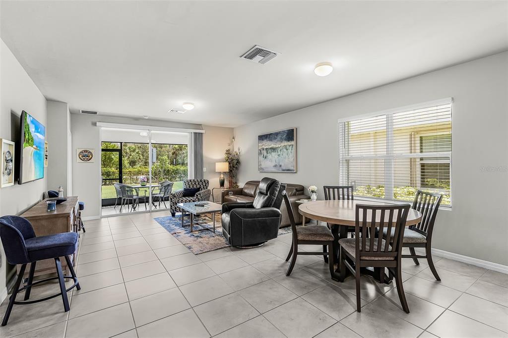 An open-concept living and dining area features tile flooring, a sliding glass door, and furniture — 25008 E LENOX CIRCLE, PUNTA GORDA, FL