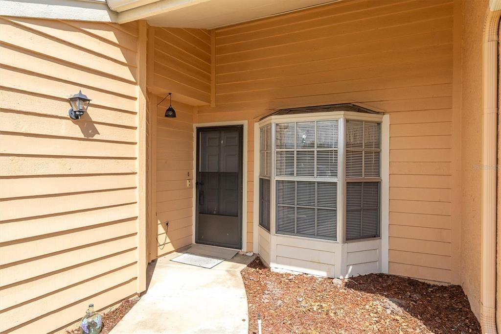 A tan house exterior features a front door, a bay window, and horizontal siding — 4968 GRIST MILL CIRCLE, NEW PORT RICHEY, FL