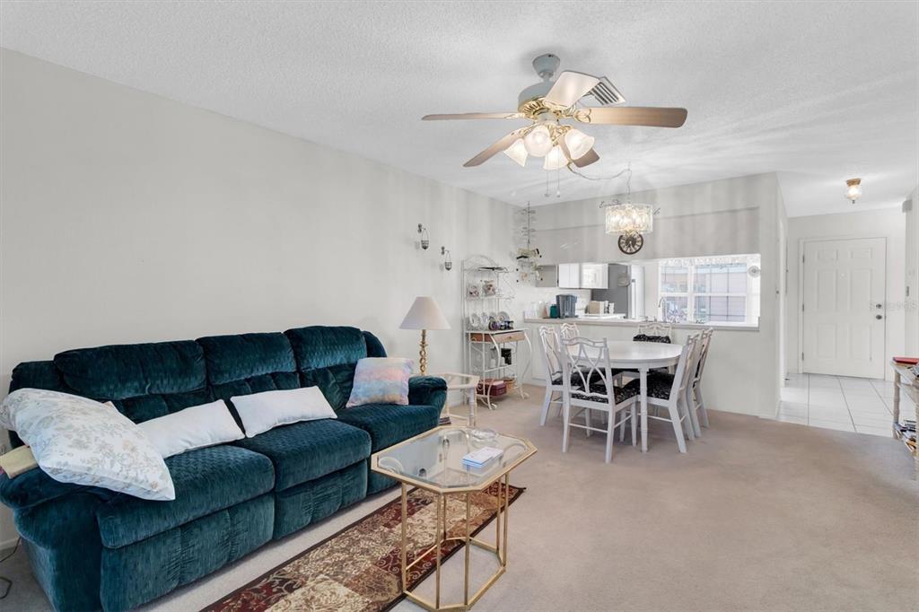 A living room with a dark blue sofa, a glass coffee table, and a dining area — 4968 GRIST MILL CIRCLE, NEW PORT RICHEY, FL