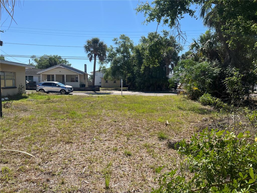 A vacant, grassy residential lot sits in front of a street with houses and trees — 1104 N GARDEN STREET, CLEARWATER, FL
