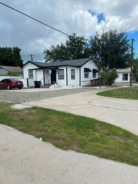 A white single-story house with a dark roof and a concrete driveway sits outdoors — 1202 N ARMENIA AVENUE, TAMPA, FL