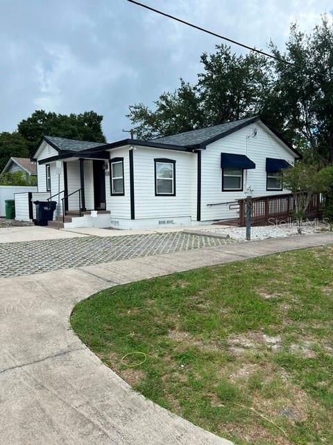 A white single-story house with black trim and a wooden deck sits on a lot — 1202 N ARMENIA AVENUE, TAMPA, FL