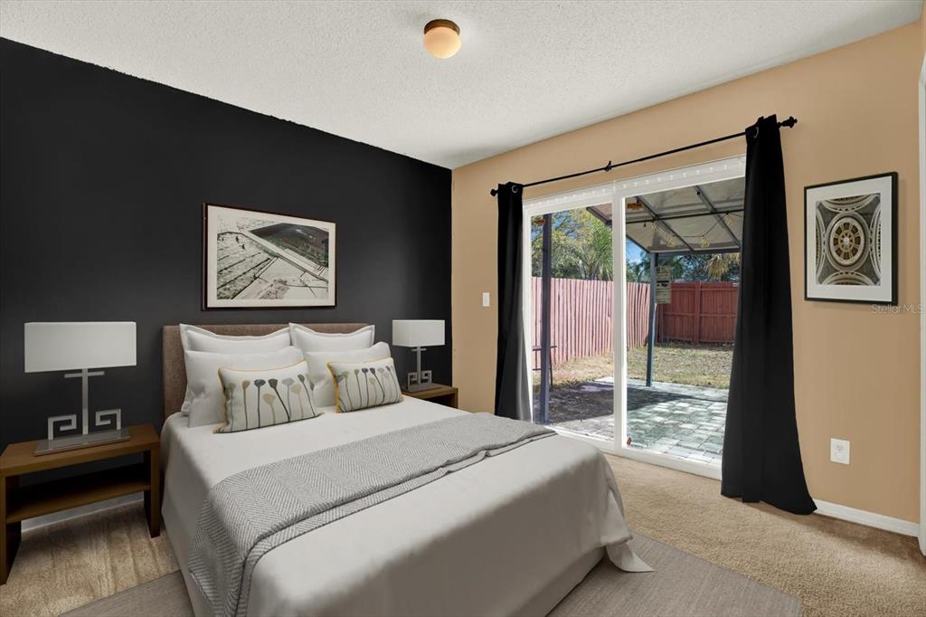 A bedroom features a black accent wall, a bed with white bedding, and sliding glass doors — 1618 CITRUS ORCHARD WAY, VALRICO, FL