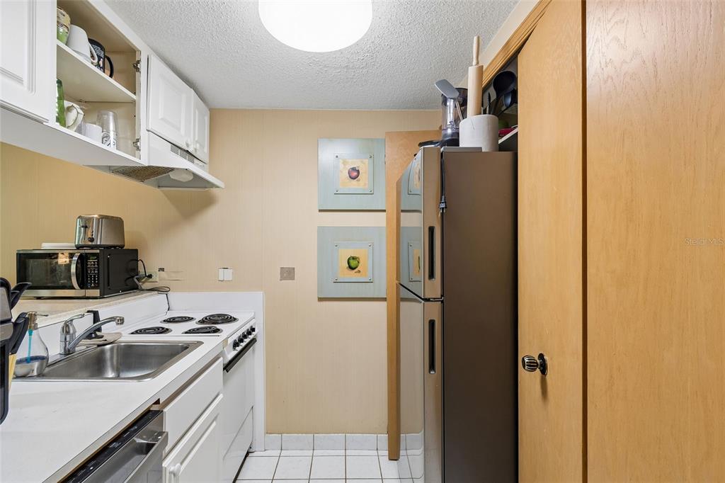 A kitchen features white cabinets, a stainless steel refrigerator, a stove, and a sink — 36750 US HIGHWAY 19 UNIT 21214, PALM HARBOR, FL