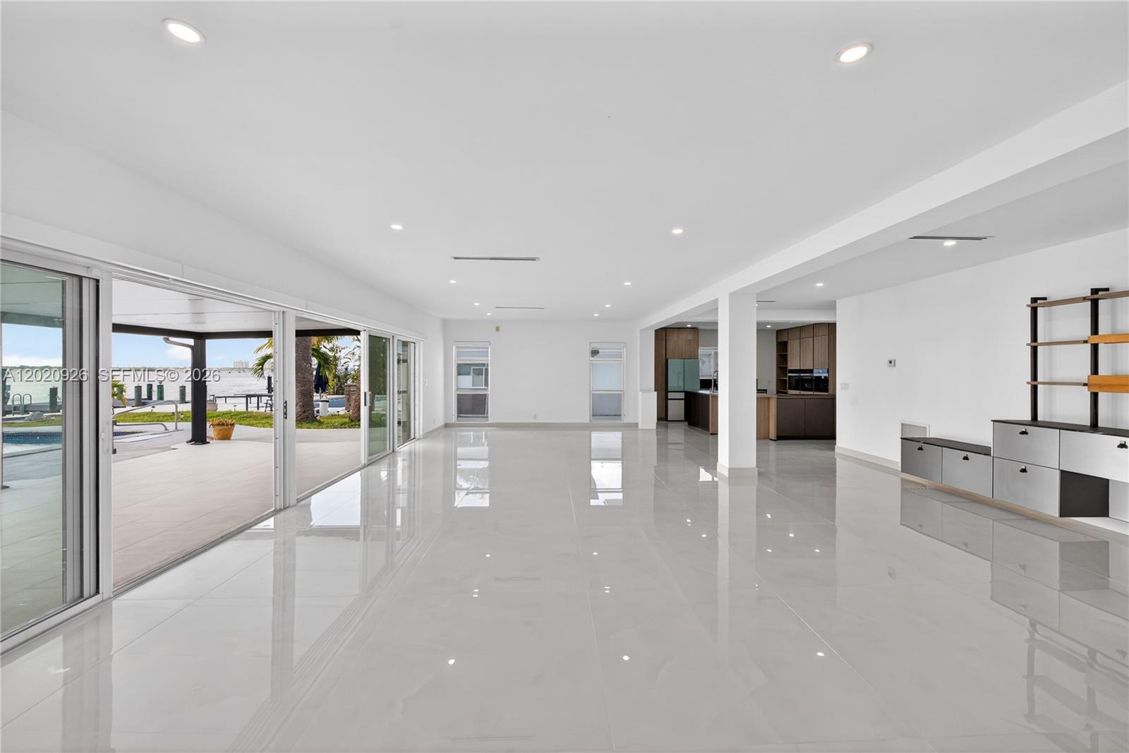 A spacious, open-concept living area features white tile floors, recessed lighting, and large sliding doors — 1101 S Shore Dr # 1, Miami Beach FL 33141, MIAMI BEACH, FL