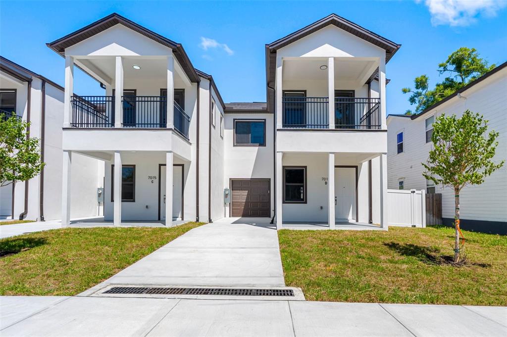 A two-story duplex building with white stucco walls, covered balconies, and a central garage — 7015 N CENTRAL AVENUE Unit D, TAMPA, FL
