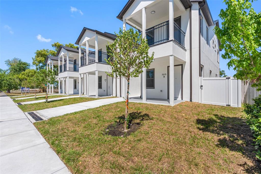 A row of modern, two-story white townhouses with balconies and concrete walkways on a sunny day — 7015 N CENTRAL AVENUE Unit D, TAMPA, FL