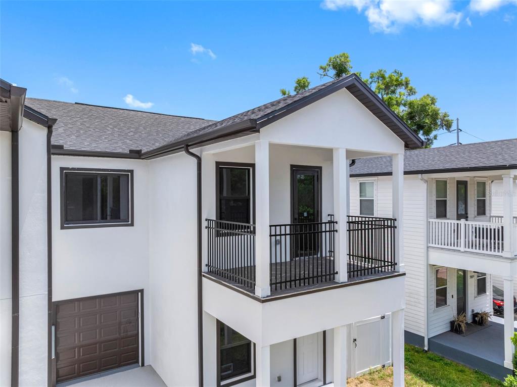 A two-story white stucco building features a second-floor balcony with black railings and a garage — 7015 N CENTRAL AVENUE Unit D, TAMPA, FL