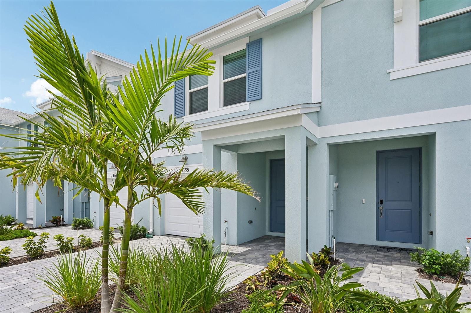 A light blue two-story townhouse features a palm tree and a paved walkway entrance — 655 Salisbury Circle, Fort Pierce FL 34982, FORT PIERCE, FL