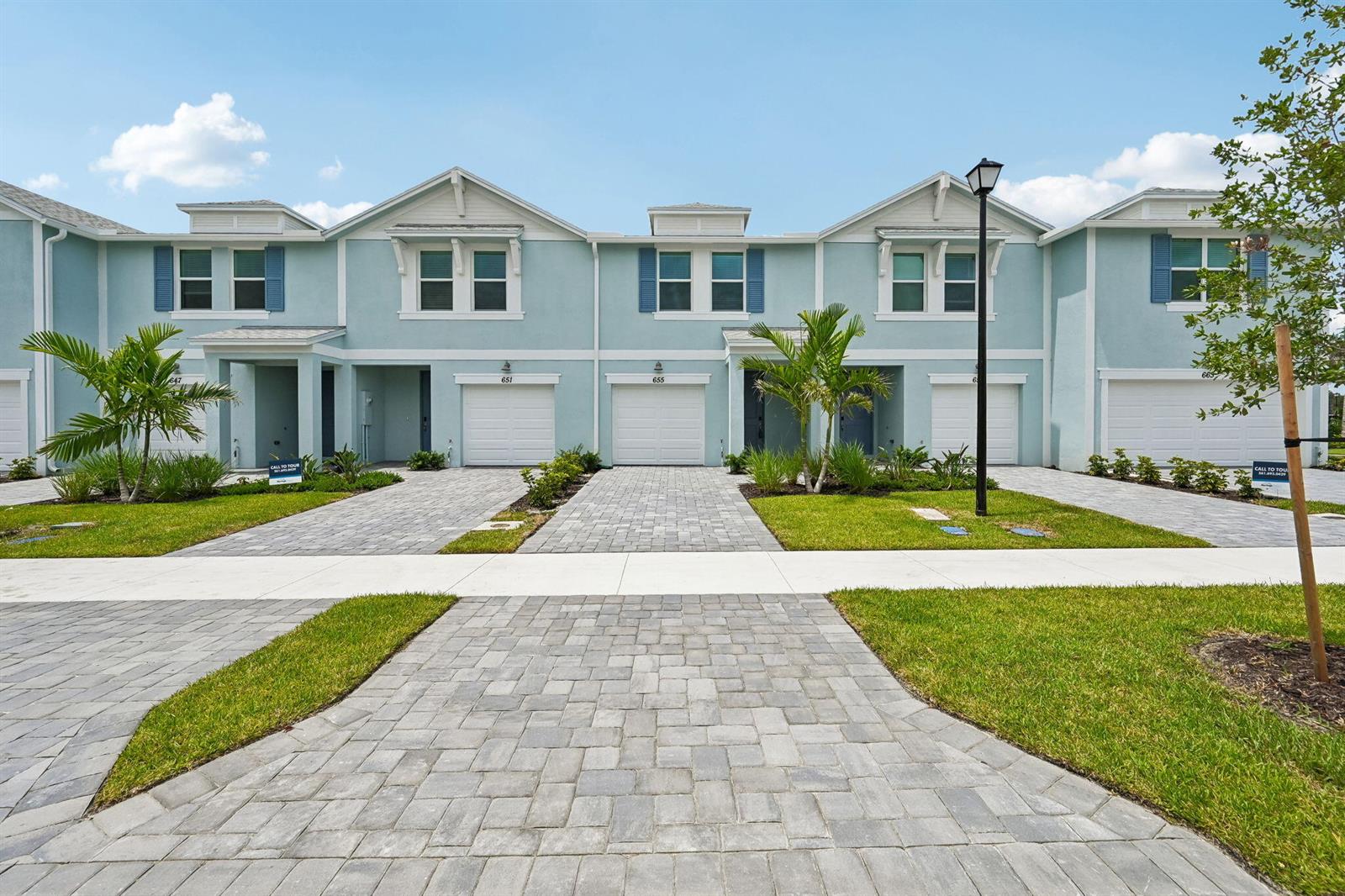 A row of light blue two-story townhomes features white garage doors and paver driveways — 655 Salisbury Circle, Fort Pierce FL 34982, FORT PIERCE, FL