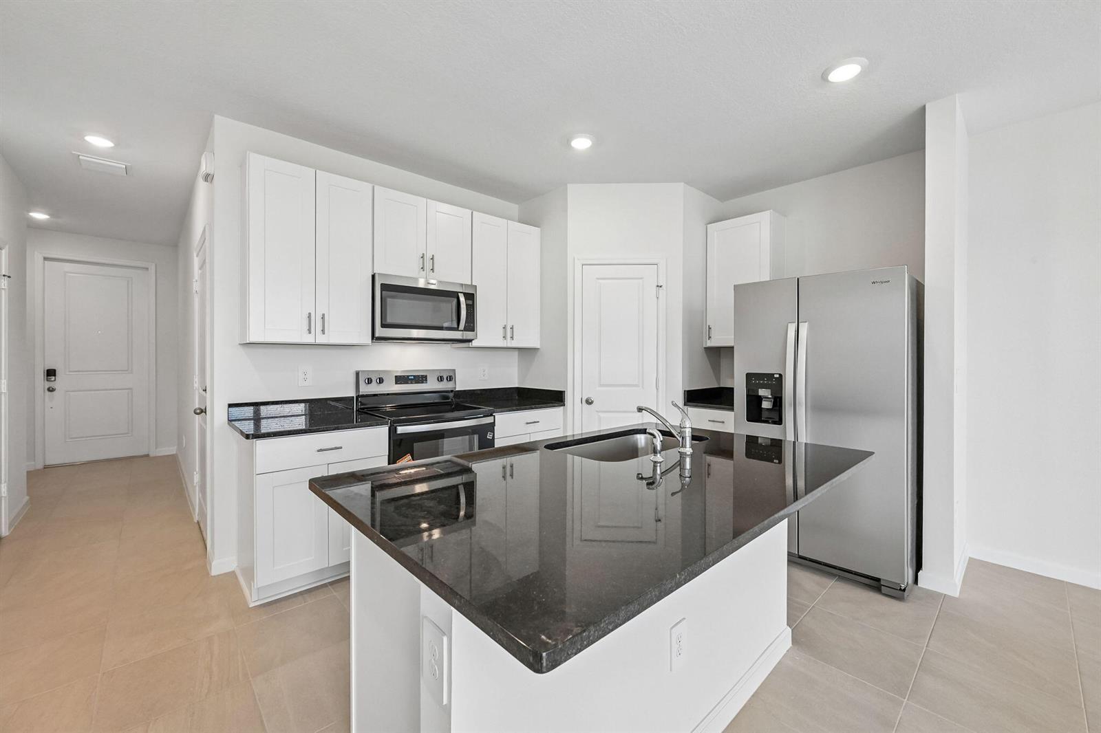 A kitchen features white cabinets, black granite countertops, stainless steel appliances, and a central island — 655 Salisbury Circle, Fort Pierce FL 34982, FORT PIERCE, FL