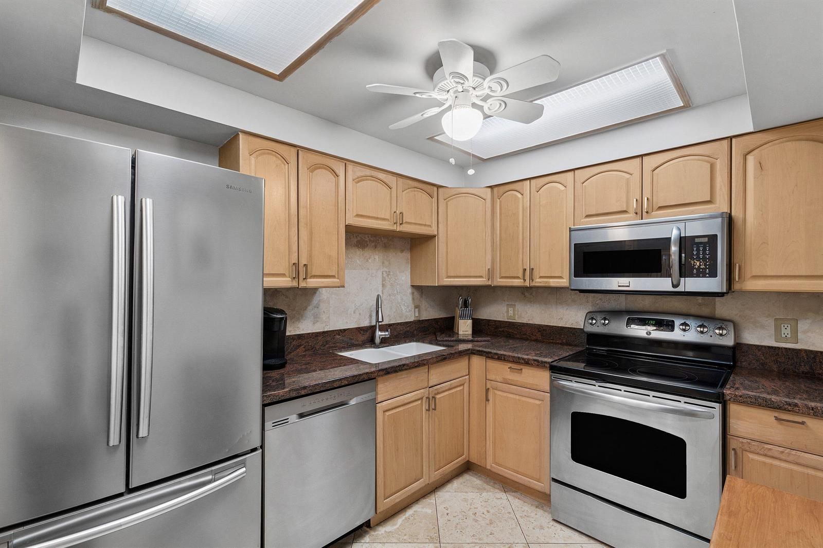 A kitchen features light wood cabinets, dark granite countertops, and stainless steel appliances — 4511 S Ocean Boulevard # 106, Highland Beach FL 33487, HIGHLAND BEACH, FL