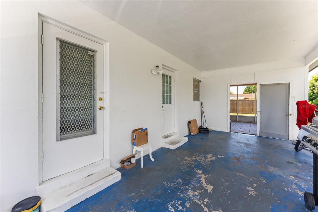 A covered patio with a blue painted concrete floor, two white doors, and a screen enclosure — 1625 HASTINGS DRIVE, DELTONA, FL