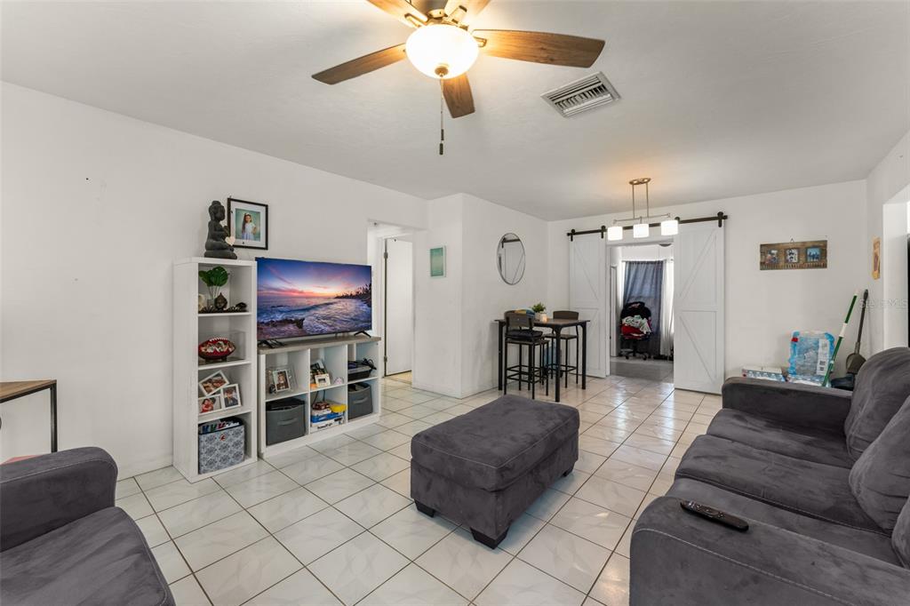 A living room with white walls, tile flooring, a ceiling fan, and a gray sofa — 1625 HASTINGS DRIVE, DELTONA, FL