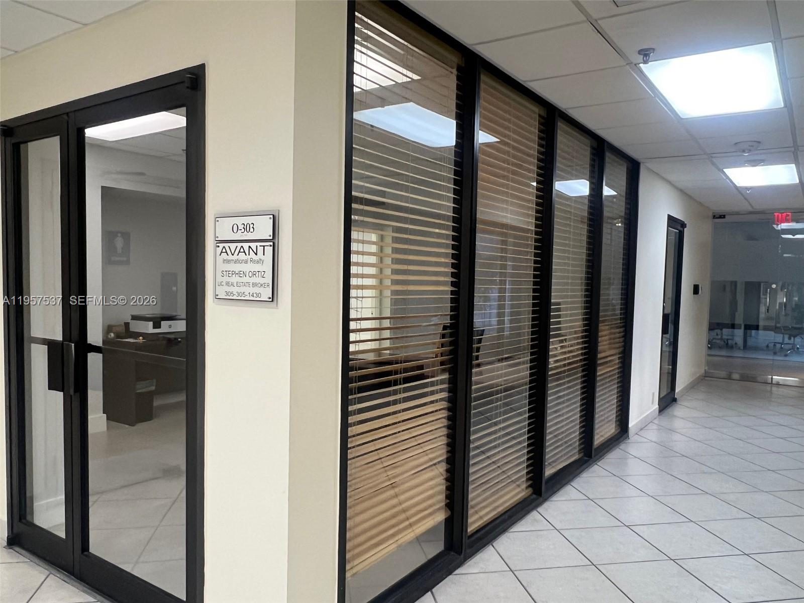 An office suite with glass walls, wooden blinds, and a sign for Avant International Realty — 520 Brickell Key Dr # O303, Miami FL 33131, MIAMI, FL