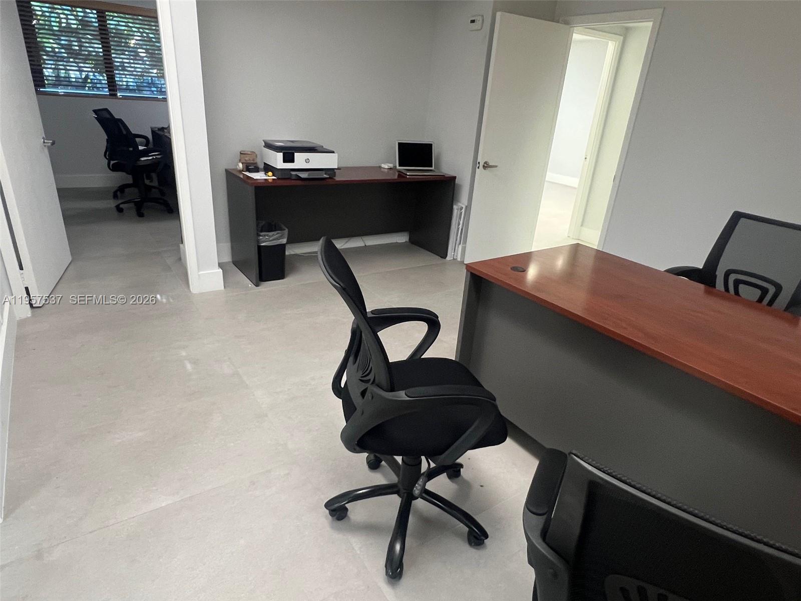 An office space features two desks, rolling chairs, and light-colored tile flooring — 520 Brickell Key Dr # O303, Miami FL 33131, MIAMI, FL
