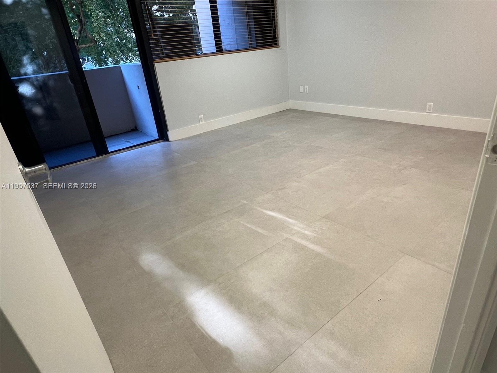 An empty room features large light gray floor tiles, white walls, and a sliding glass door — 520 Brickell Key Dr # O303, Miami FL 33131, MIAMI, FL