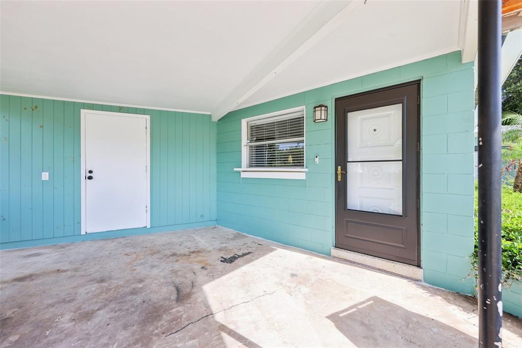 A living room with wood-look tile flooring, a white front door, and a kitchen pass-through — 1417 E HARDING STREET, ORLANDO, FL