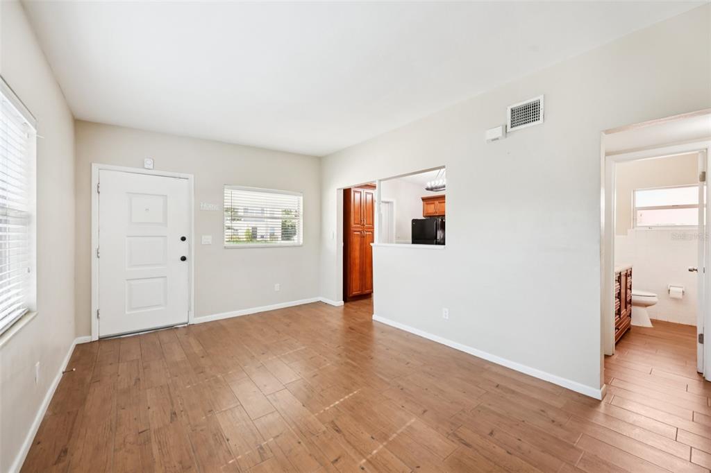 An empty room features light-colored walls, wood-look tile flooring, two windows with blinds, and a door — 1417 E HARDING STREET, ORLANDO, FL
