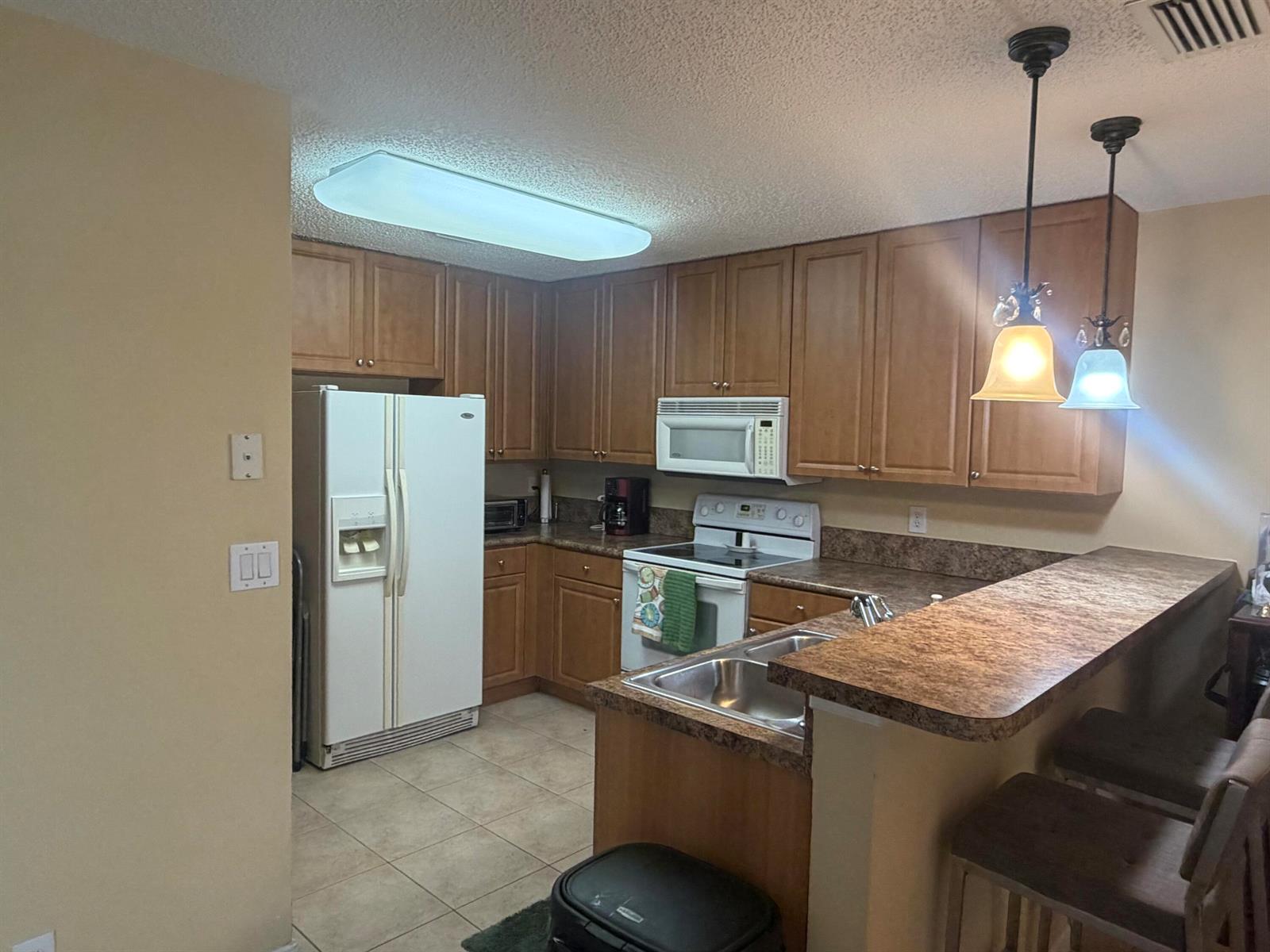 A dining room features a chandelier, a table with chairs, and an adjacent kitchen — 6718 Duval Avenue, West Palm Beach FL 33411, WEST PALM BEACH, FL