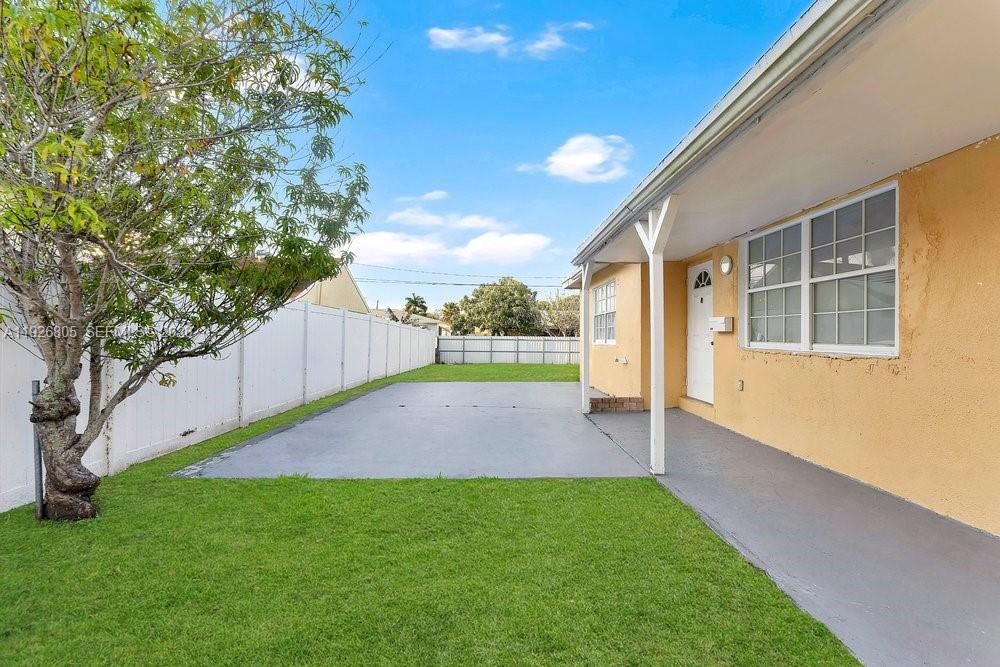 A backyard features a concrete patio, a grass lawn, and a white privacy fence — 417 SW 3rd St, Hallandale Beach FL 33009, HALLANDALE BEACH, FL
